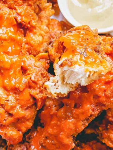 Buffalo chicken tenders on a plate with dipping sauce.