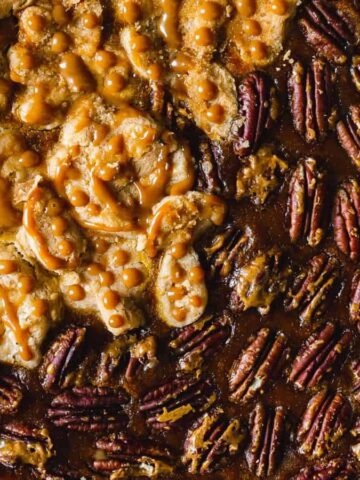 A pie with a half-and-half topping: on one side, caramel and walnuts; on the other, a layer of pecans. The crust is light brown and the pie rests on a burlap surface.