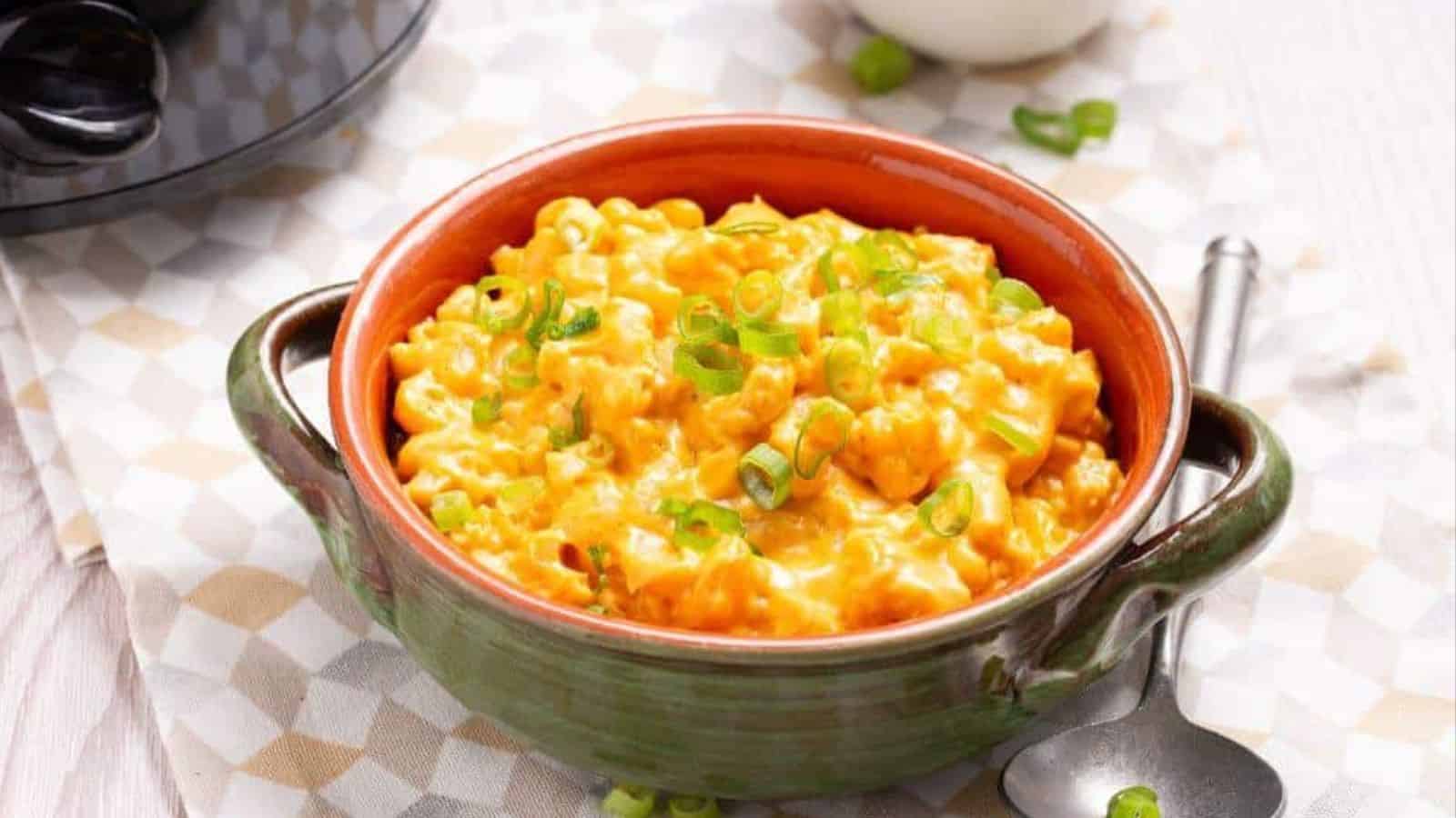 A bowl of macaroni and cheese in front of a slow cooker.
