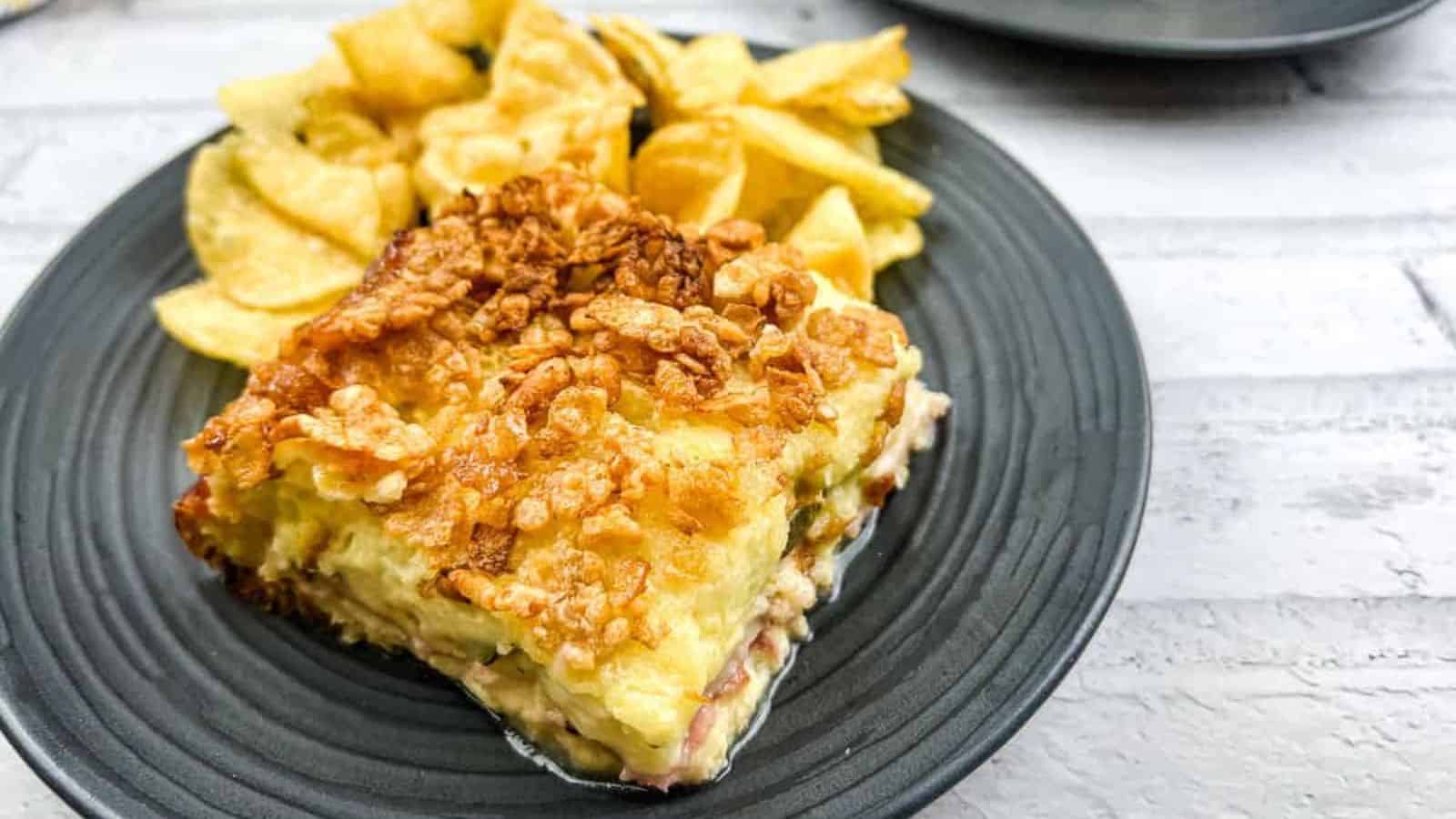 A piece of Cuban sandwich casserole on a plate with potato chips.