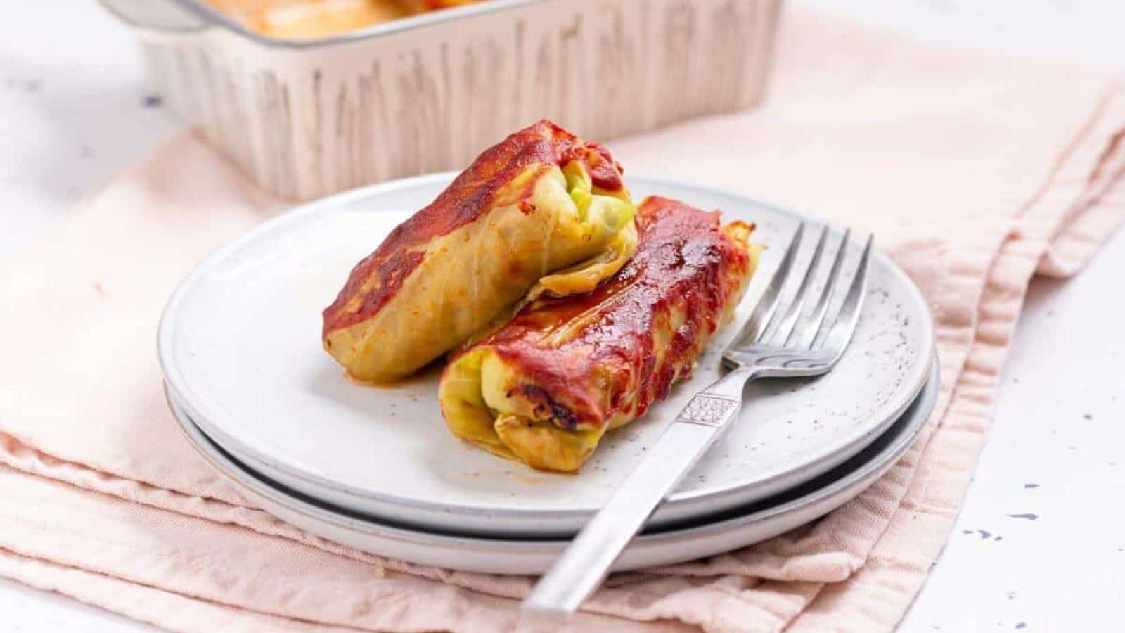 Two cabbage rolls on a plate with fork.