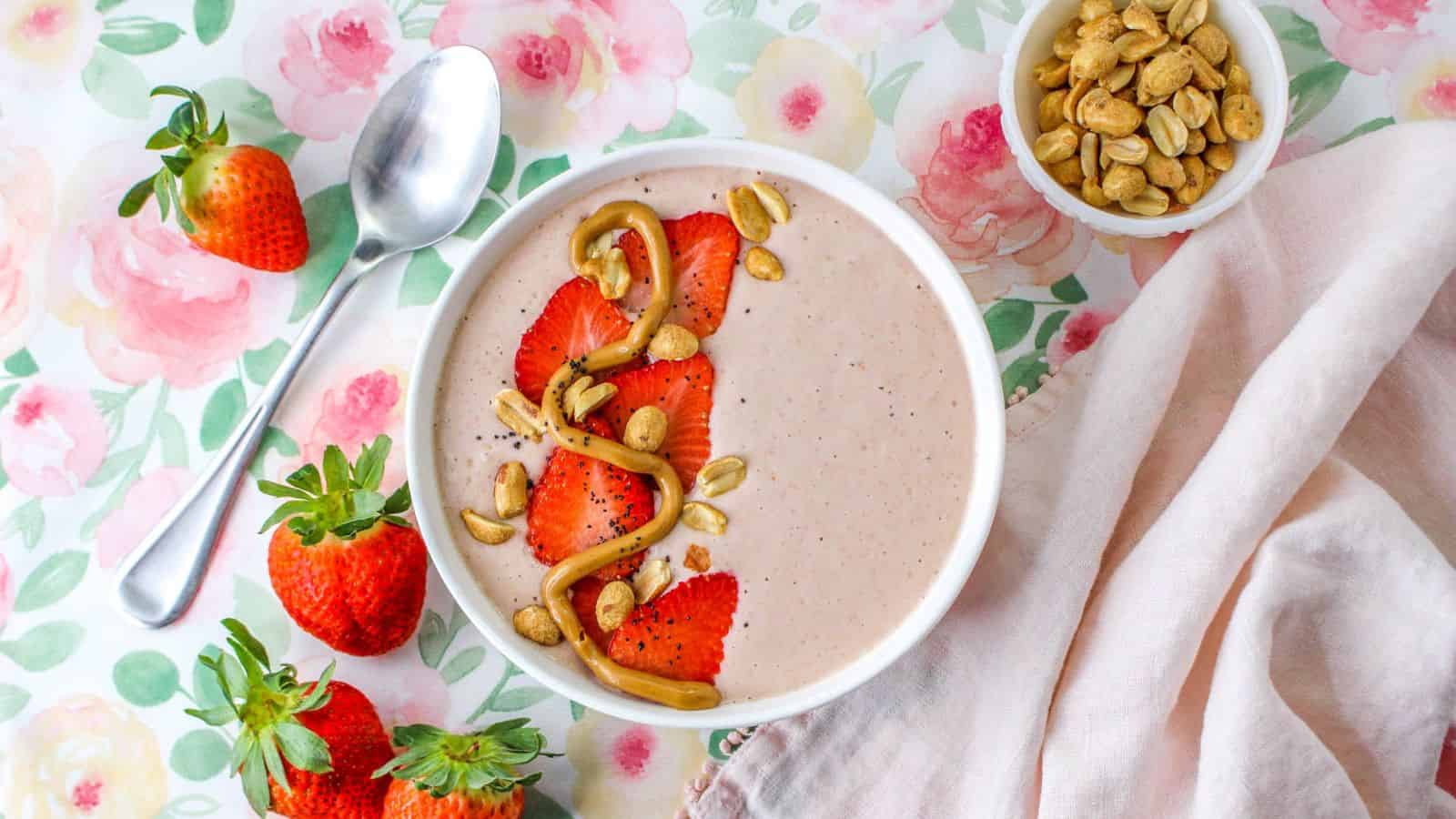 Smoothie  topped with strawberries, peanuts, and peanut butter swirl in bowl.