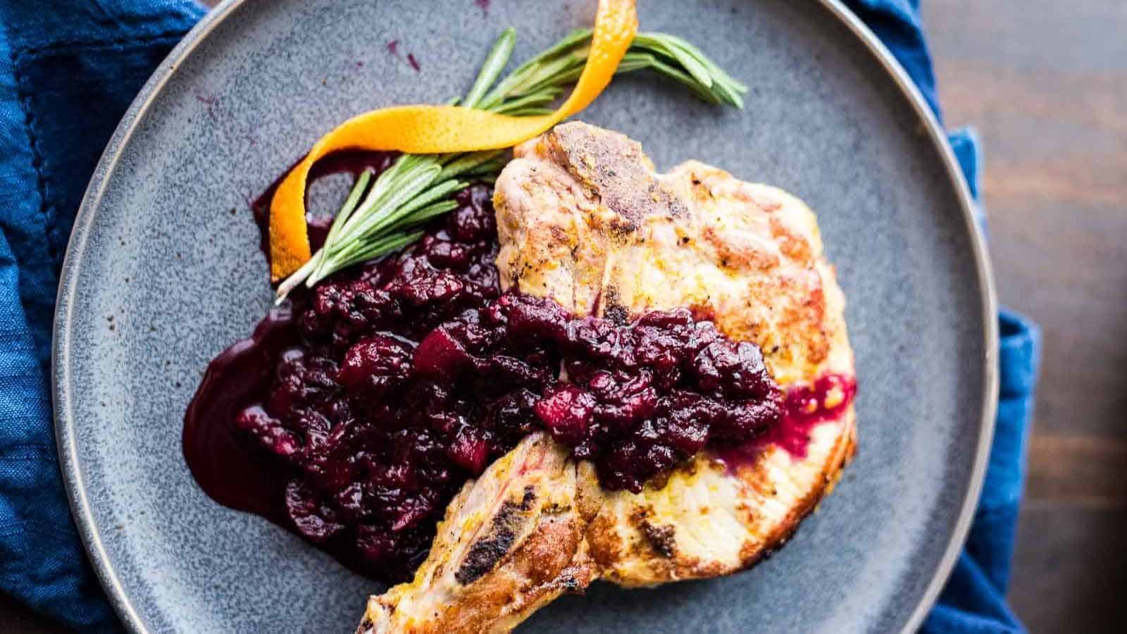 Pork chops with blackberry applesauce on a gray plate.