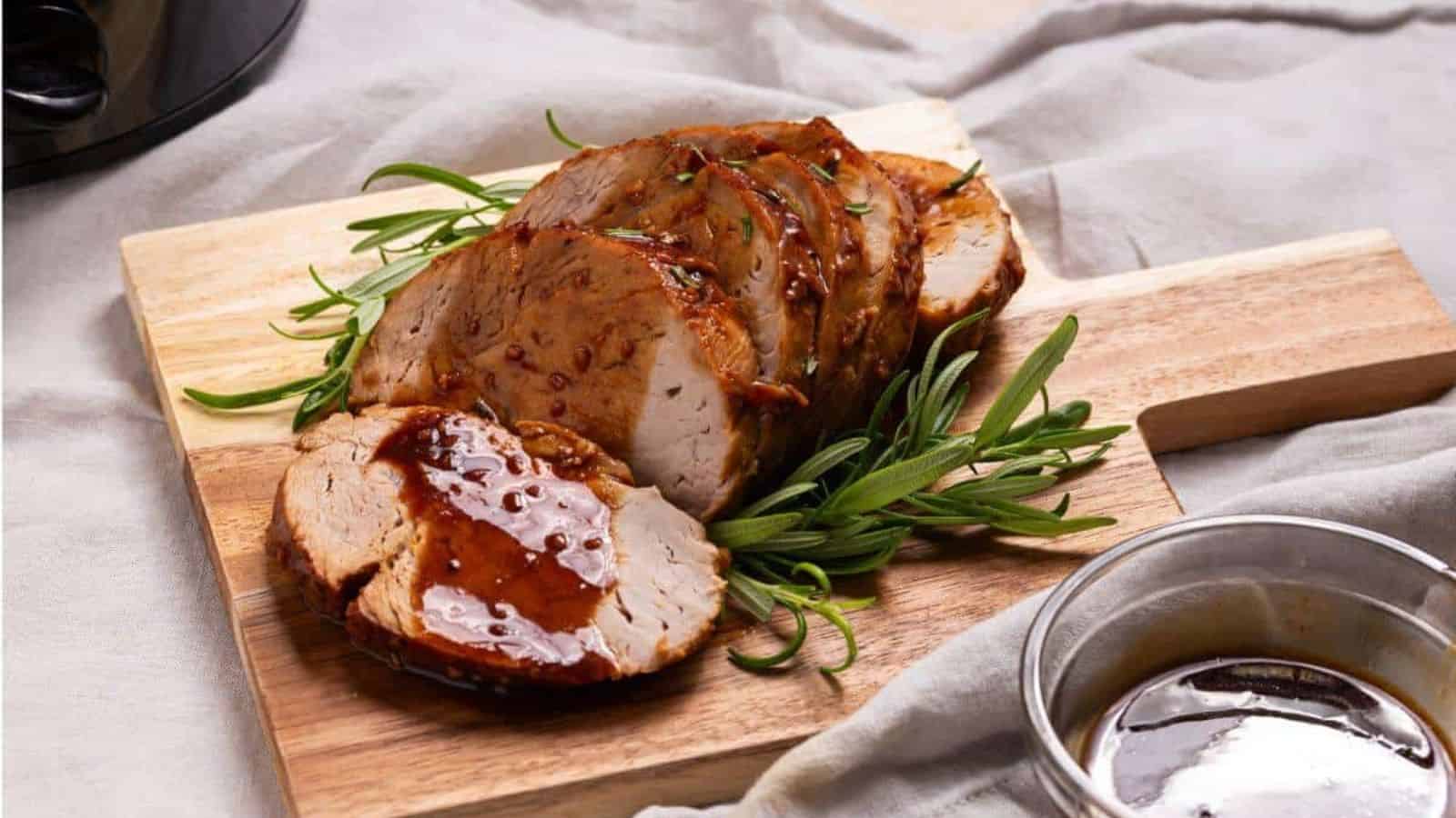 Pork tenderloin on a cutting board next to a slow cooker.