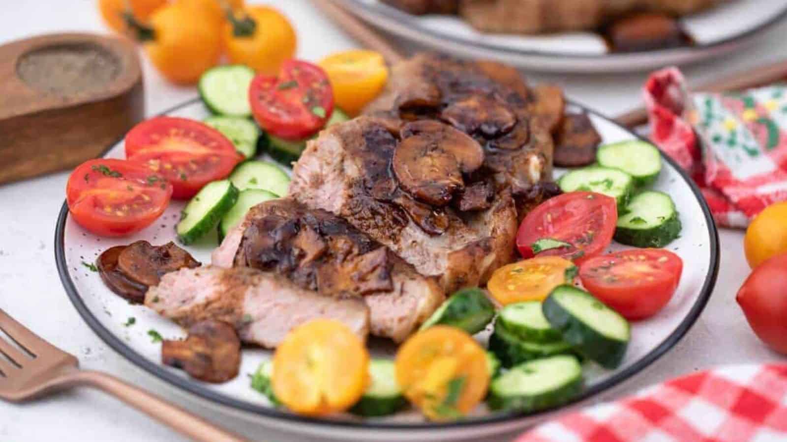 A plate with steak, tomatoes and cucumbers on it.
