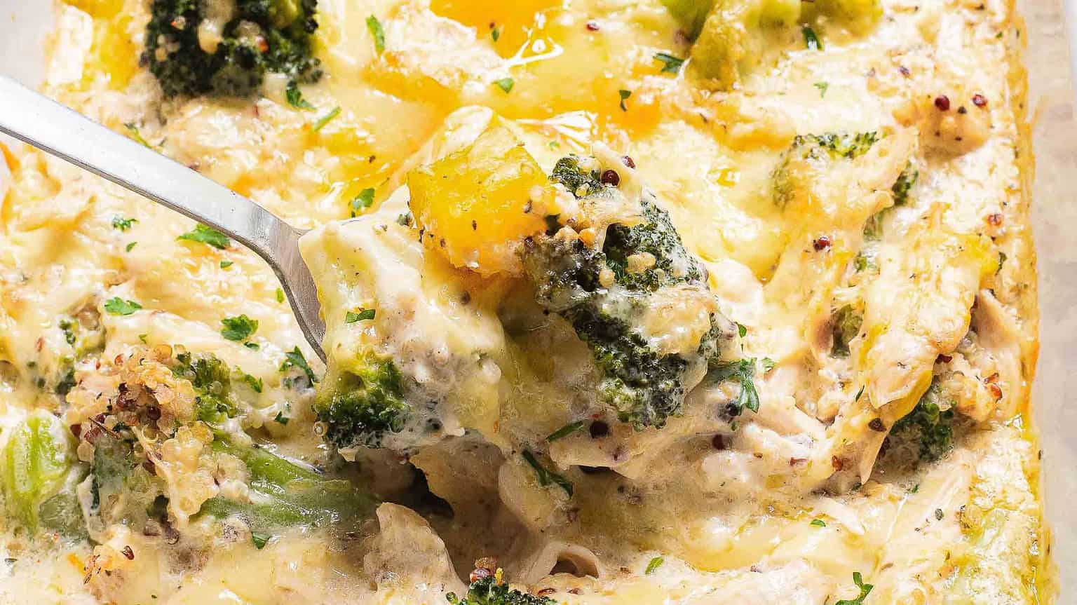 A spoonful of creamy chicken and broccoli casserole, topped with cheese and garnished with parsley, ready to be served.
