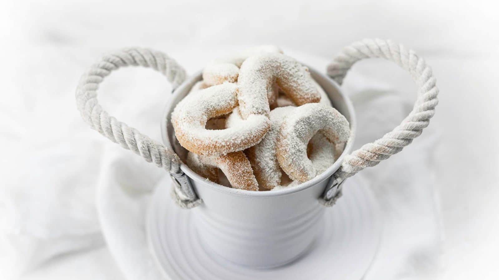 Almond Crescent Cookies on a parchment paper with one piece missing.