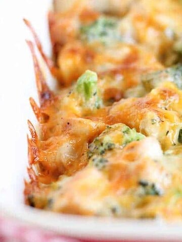 A comforting dish featuring a baked casserole in a white dish, with melted cheese mixed with broccoli and chunks of chicken. The browned, slightly crispy top layer evokes a favorite childhood memory of meals just out of the oven.