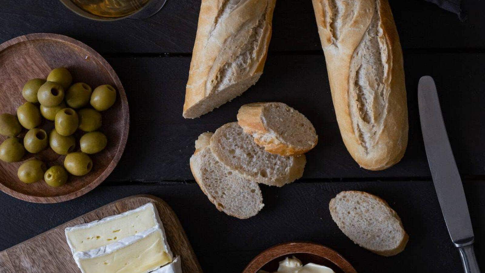 Bread, olives, and cheese on a wooden table.