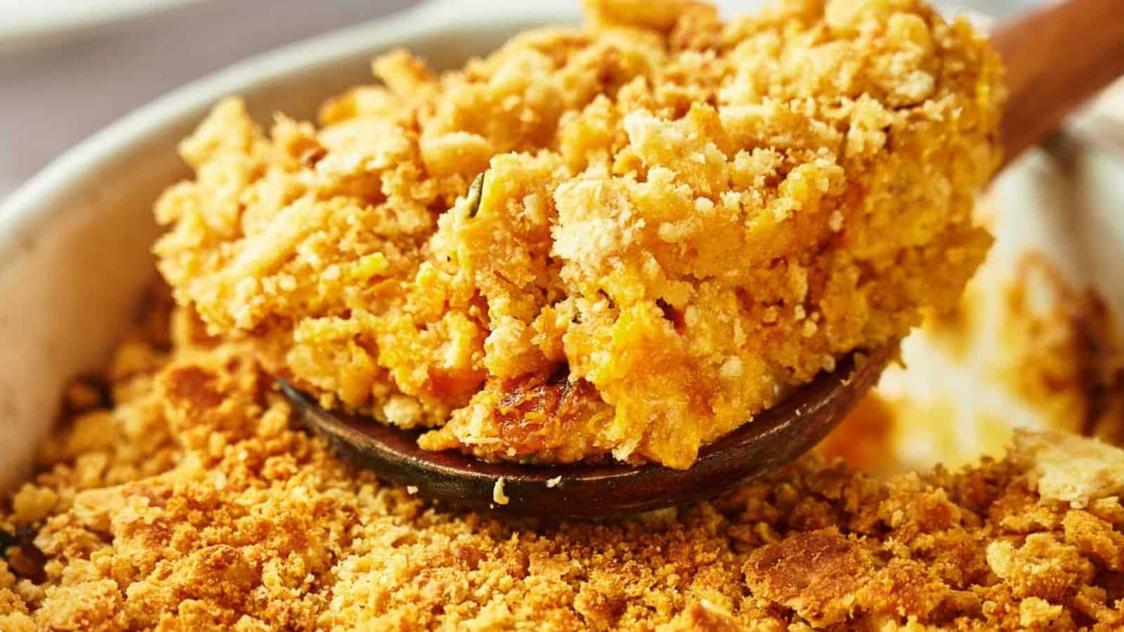 Close-up of a spoon scooping a portion of crumbly, golden-brown topping from a dish. The texture is coarse, suggesting a baked dessert or casserole, with the spoon nestled among the crispy topping.