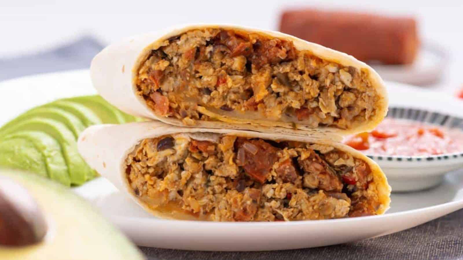 Breakfast chorizo burrito sliced in half on plate.