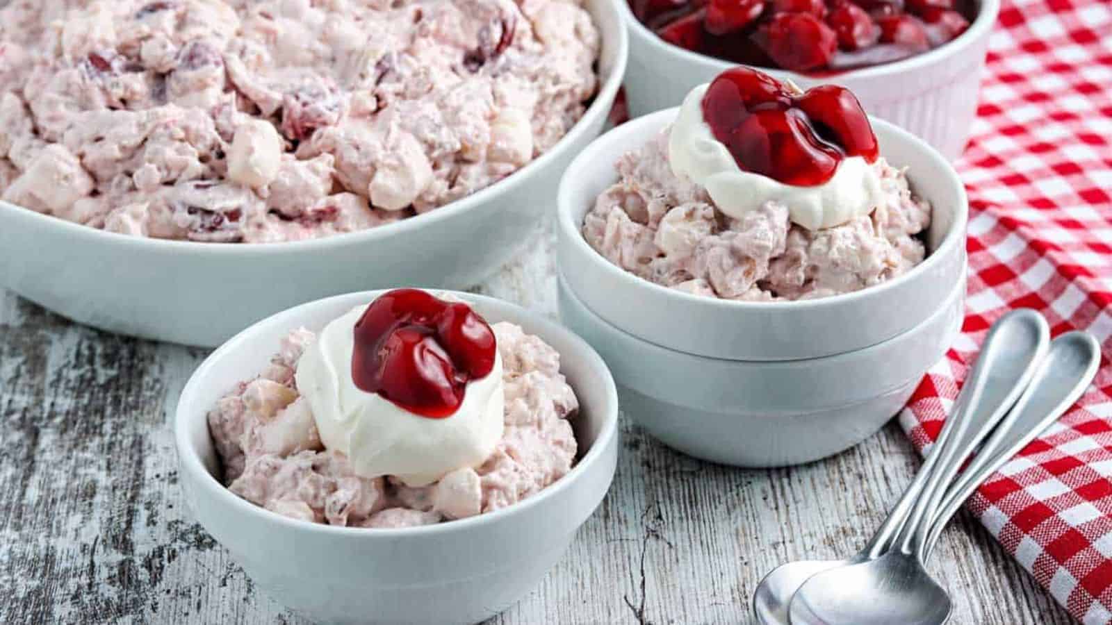 Cherry fluff salad in blue bowls with whipped cream.