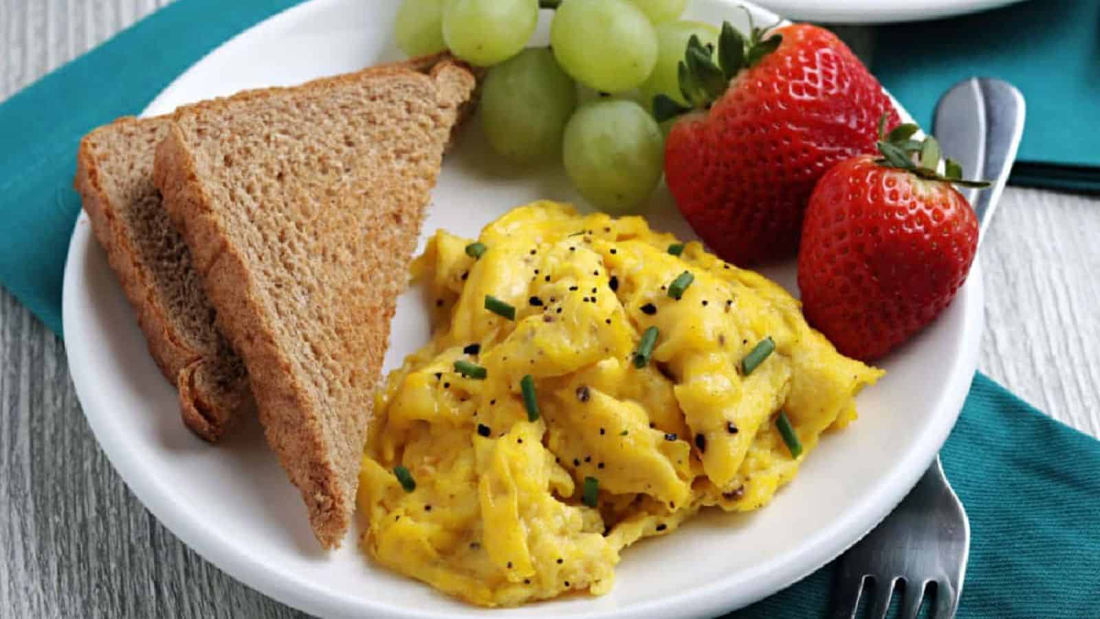 A white plate with scrambled eggs and toast.