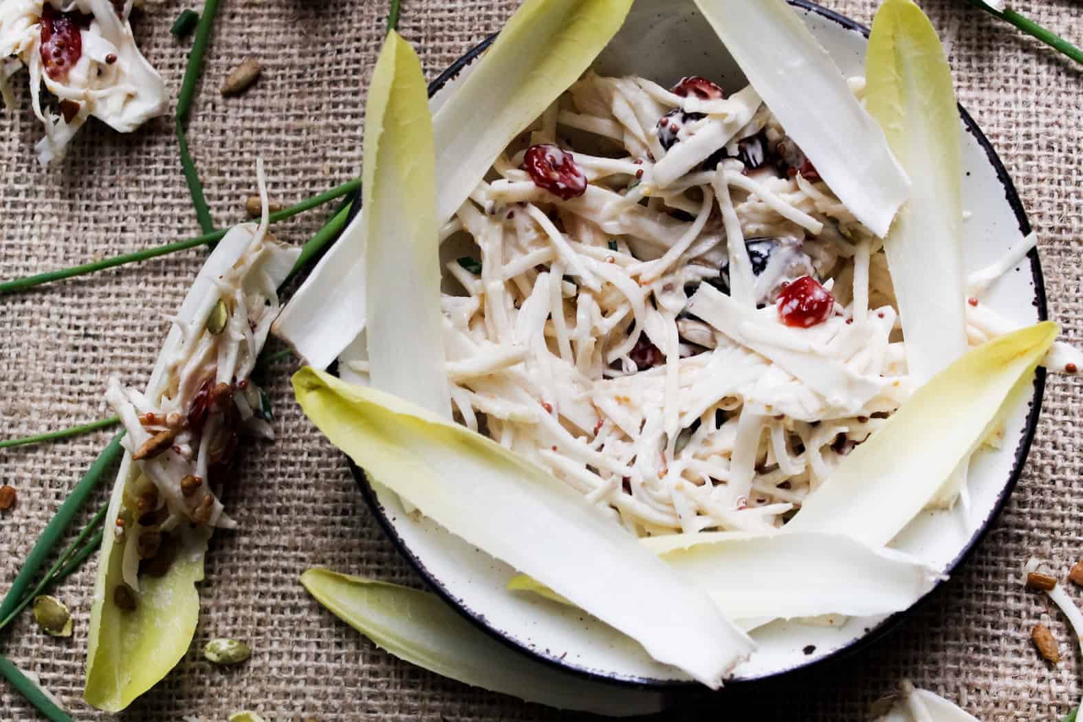 A wooden platter with sliced apples and cranberries.