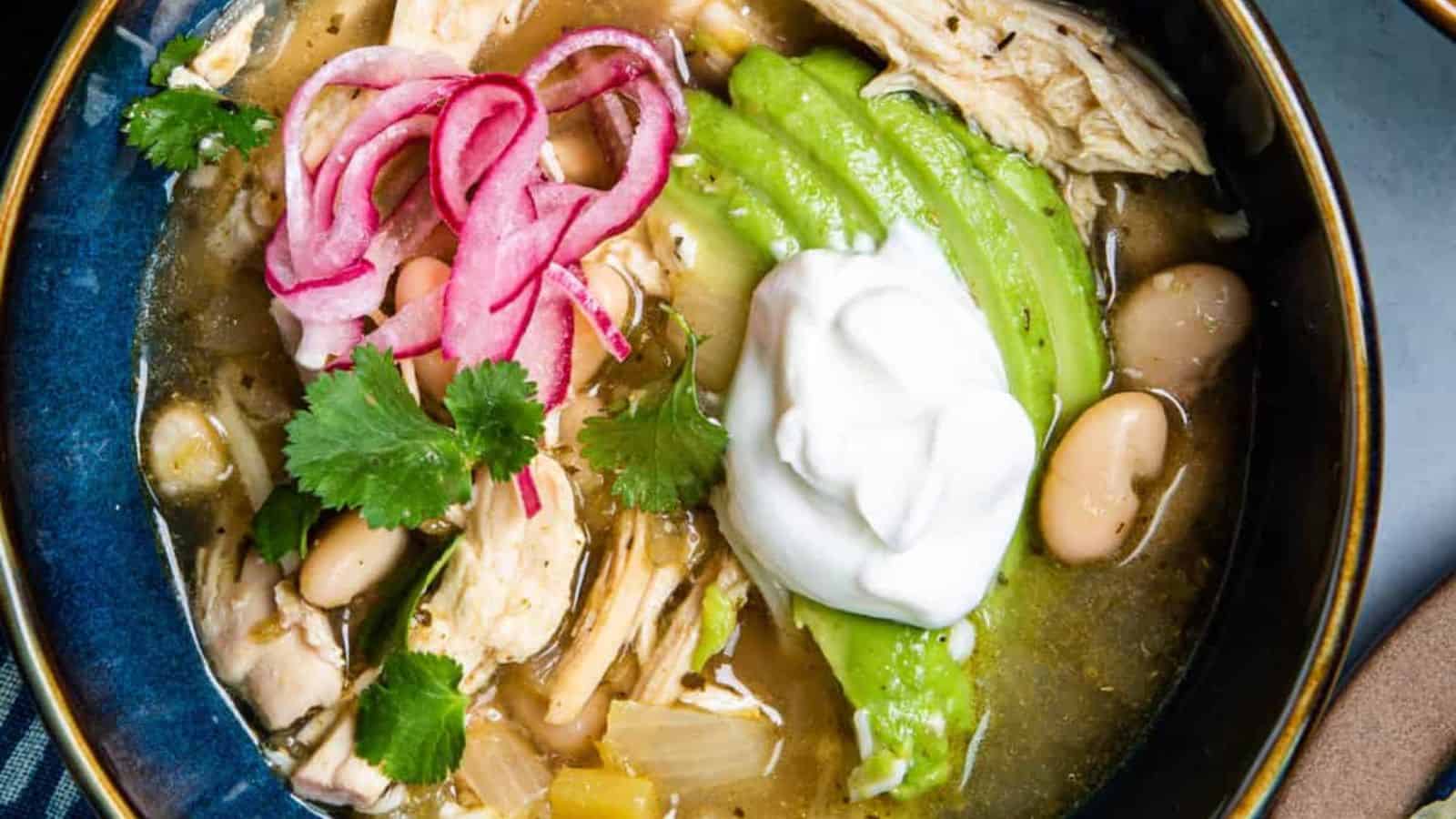 Overhead shot of a pot of the soup with two bowls of the soup and garnishes.