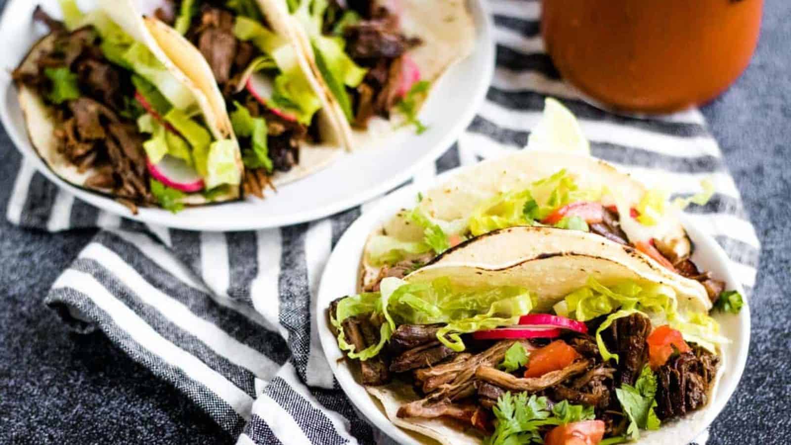 Mexican beef tacos on white plates.