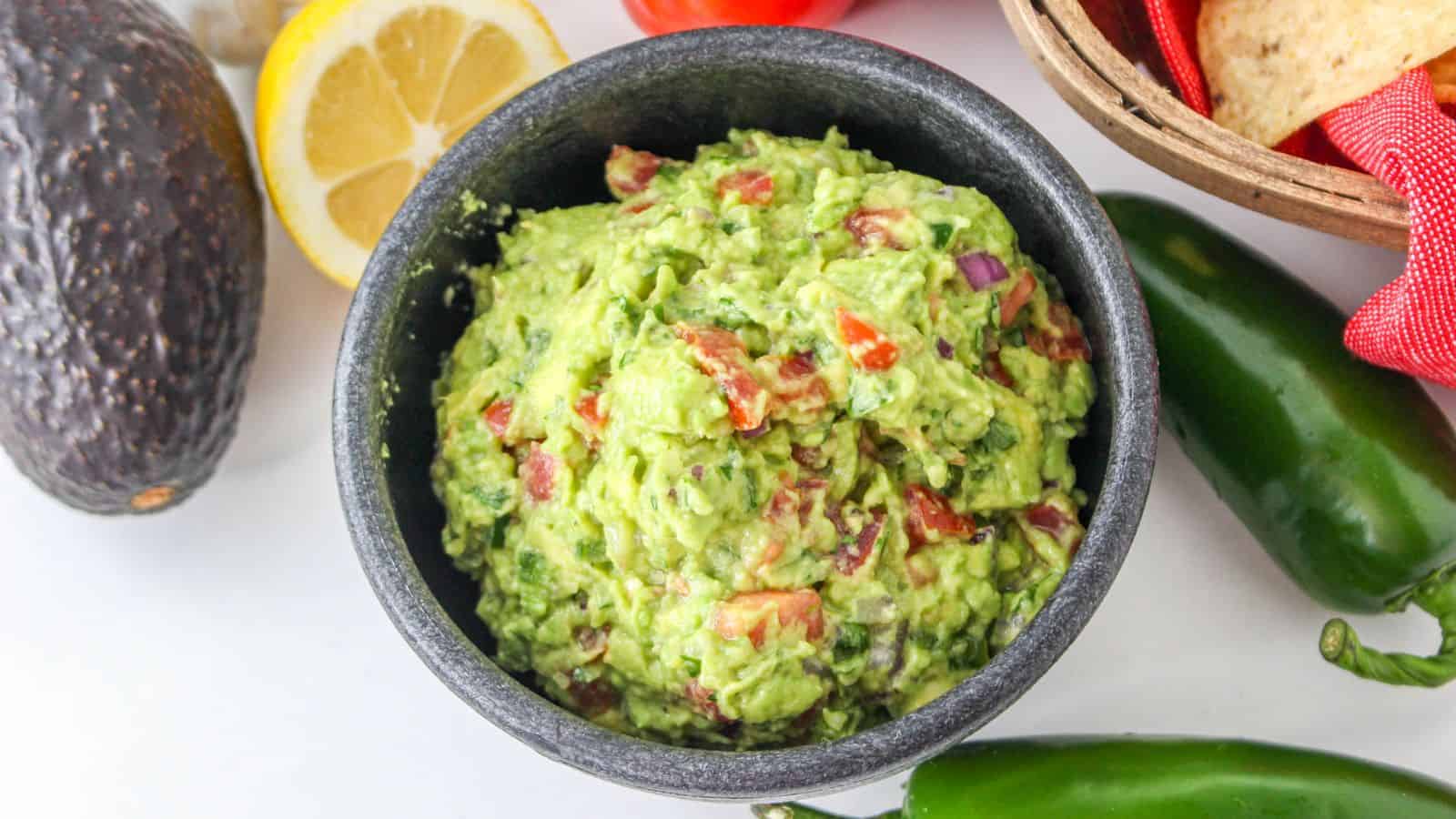 Mexican dip in a dark bowl with avocados and jalapenos.