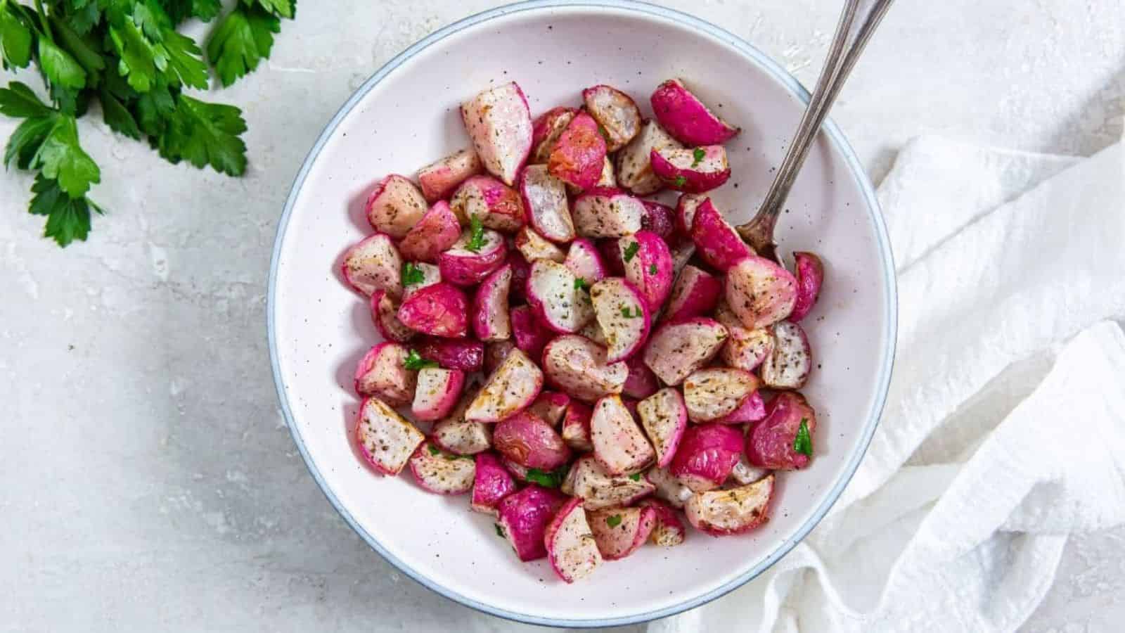Air Fryer Radishes with parsley, salt, and pepper in a white bowl with a spoon.