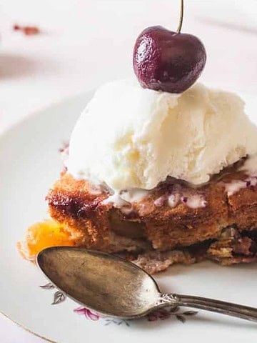 Side view of a slice of cherry cobbler with ice cream.