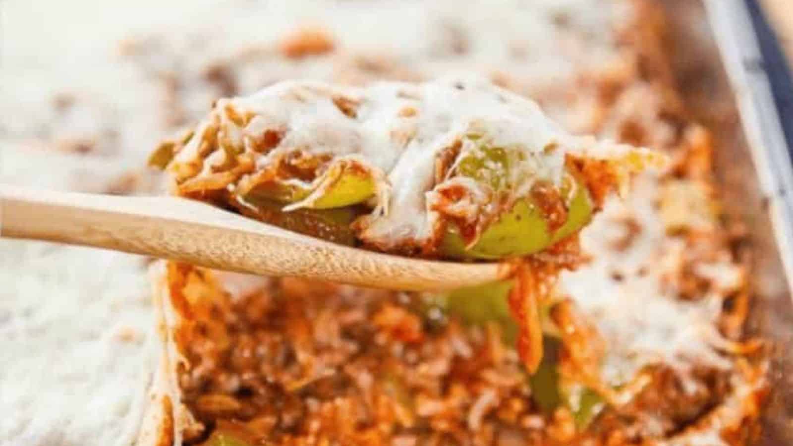 A spoon lifting out stuffed pepper casserole topped with mozzarella cheese.