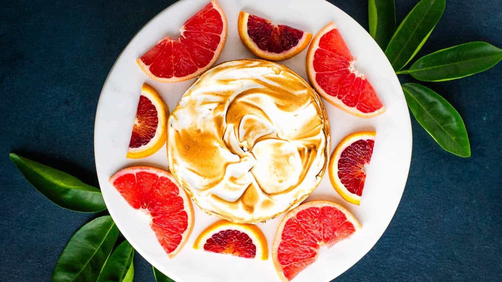 A plate with Citrus Dream Tart next to slices of grapefruit and blood orange.