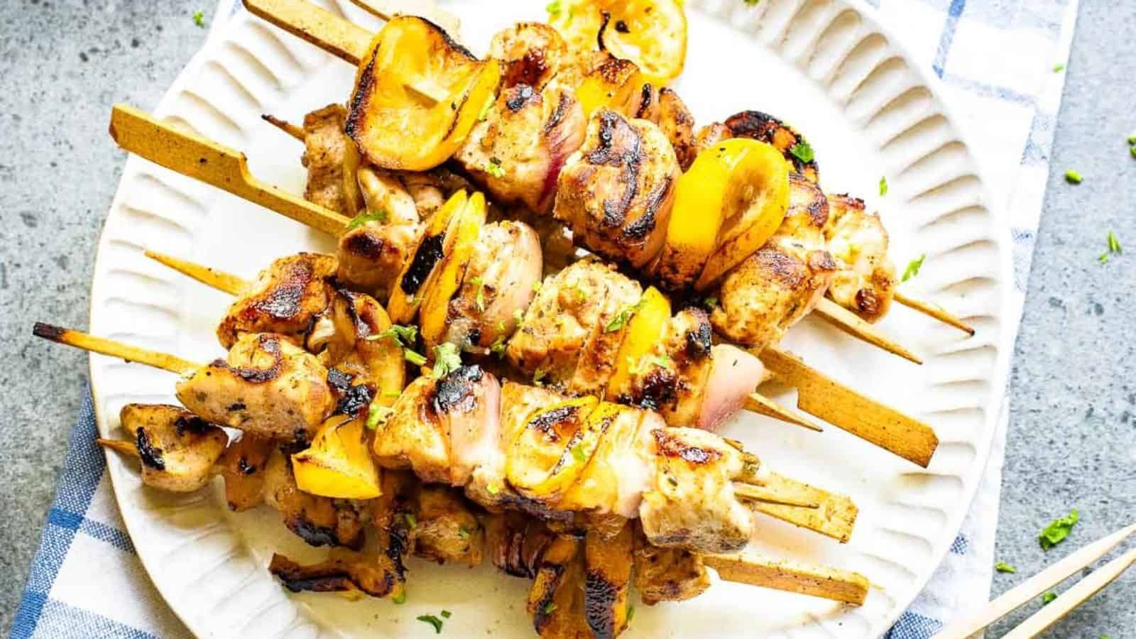 Grilled Greek lemon chicken kabobs with herbs and lemon slices.