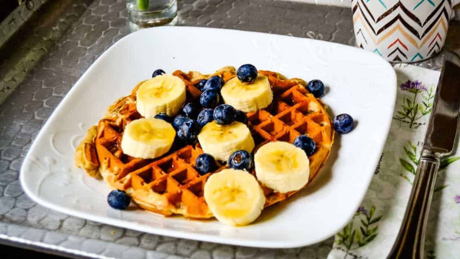 A plate of banana waffles with bananas and blueberries.