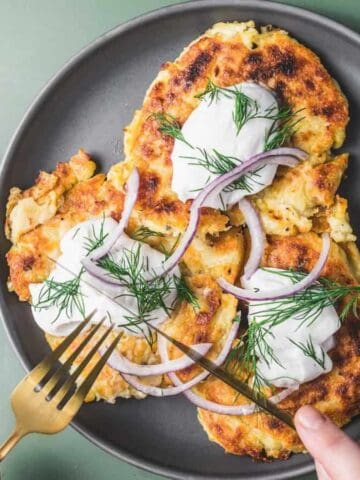 Irish boxy potato pancakes on a plate, and sliced onions in a small bowl beside them.