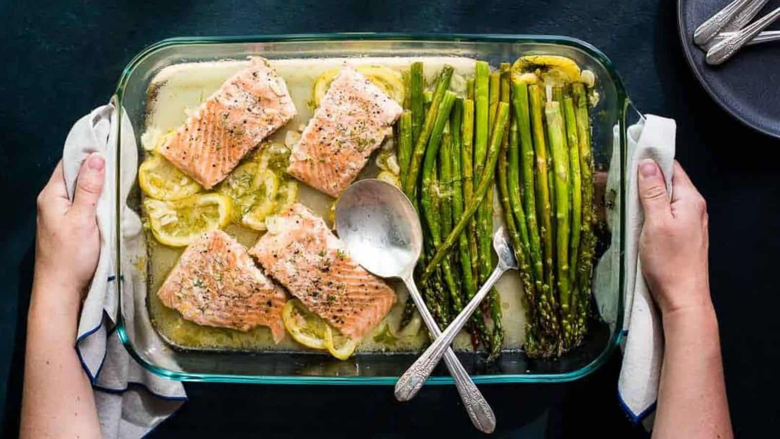 Hands holding a baking dish with Lemon Dill Salmon and Asparagus.
