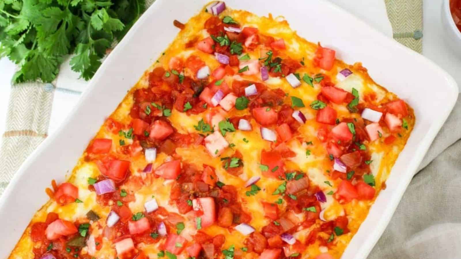 Casserole dish with melted cheese, diced tomatoes, onions, and chopped cilantro on top, with a side bowl of salsa and cilantro garnish nearby.
