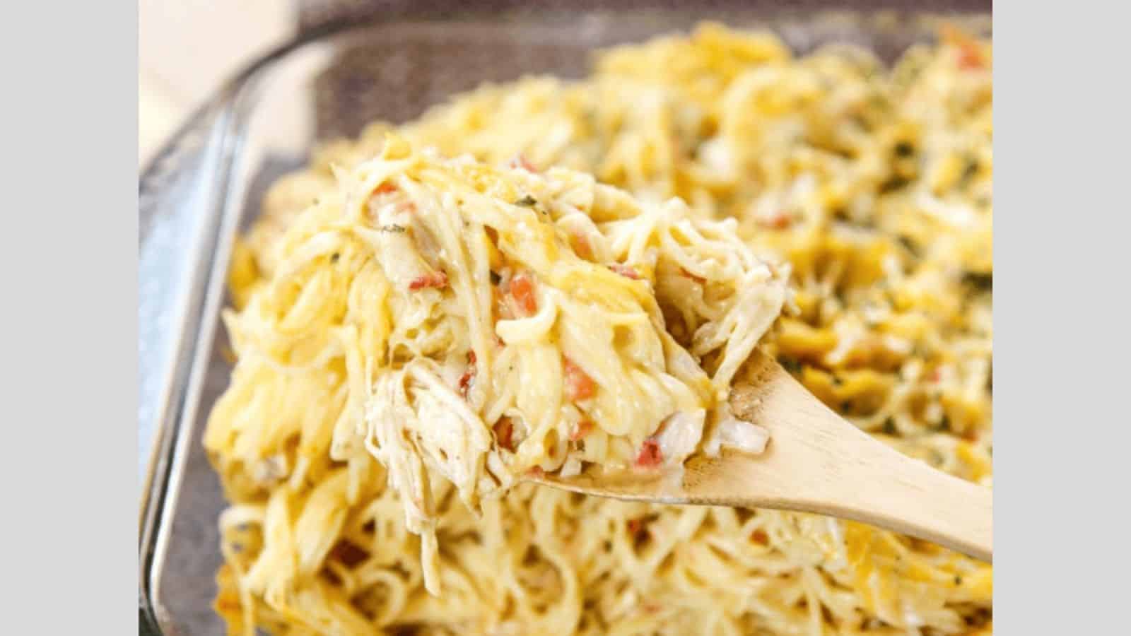 A wooden spoon lifting spaghetti our a casserole dish with a wooden spoon.