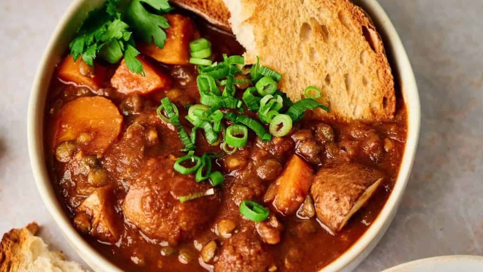 A bowl of stew with bread and carrots.