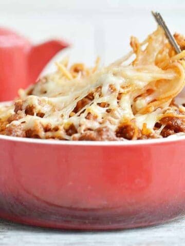 A red dish of spaghetti casserole with a fork in it, to the side.