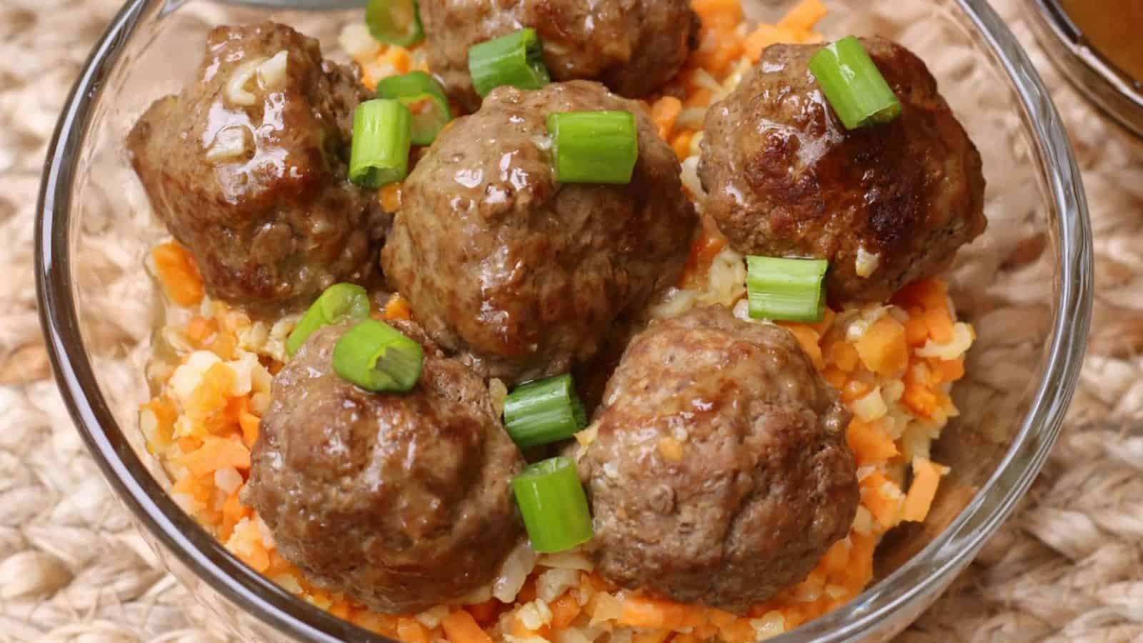 Clear bowl of riced veggies and meatballs.