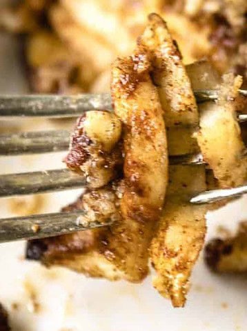 A fork holds spiced apple slices with oat crumble, close-up, with more crumble in the background.