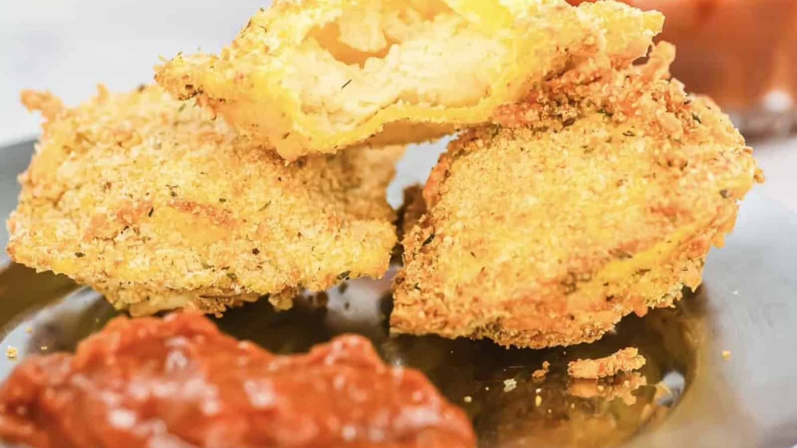A hand dips a crispy, breaded zucchini chip into a bowl of marinara sauce.