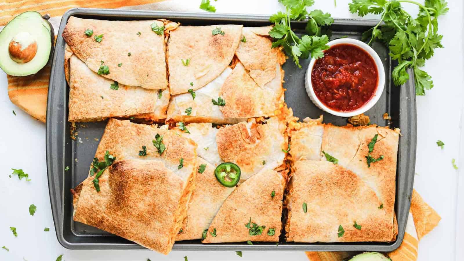 Stack of chicken quesadilla wedges with cilantro garnish.