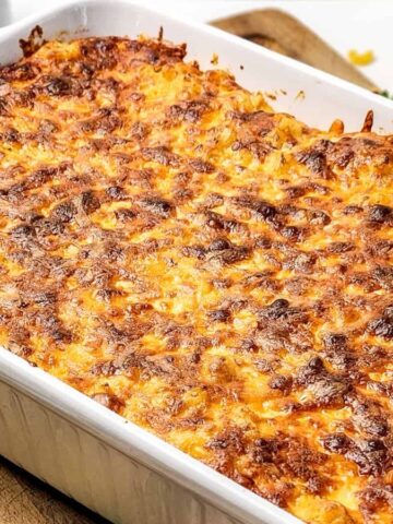 Baked macaroni and cheese in a white casserole dish with a golden, crispy cheese topping.