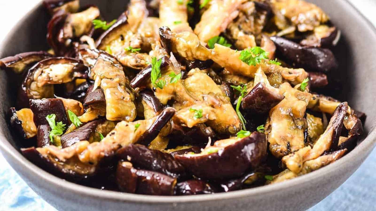 A bowl of pickled eggplant slices with garlic and spices.