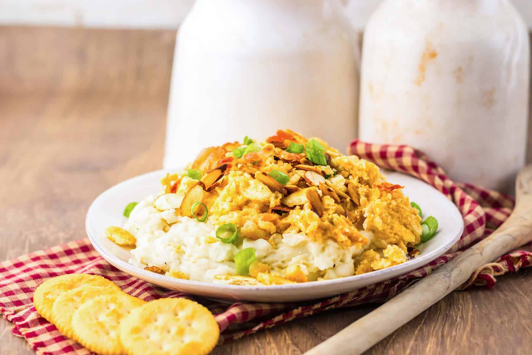 A plate with creamy scrambled eggs, mashed potatoes, green onions, and crackers on the side&mdash;perfect alongside tender slow cooker Neiman Marcus Chicken.