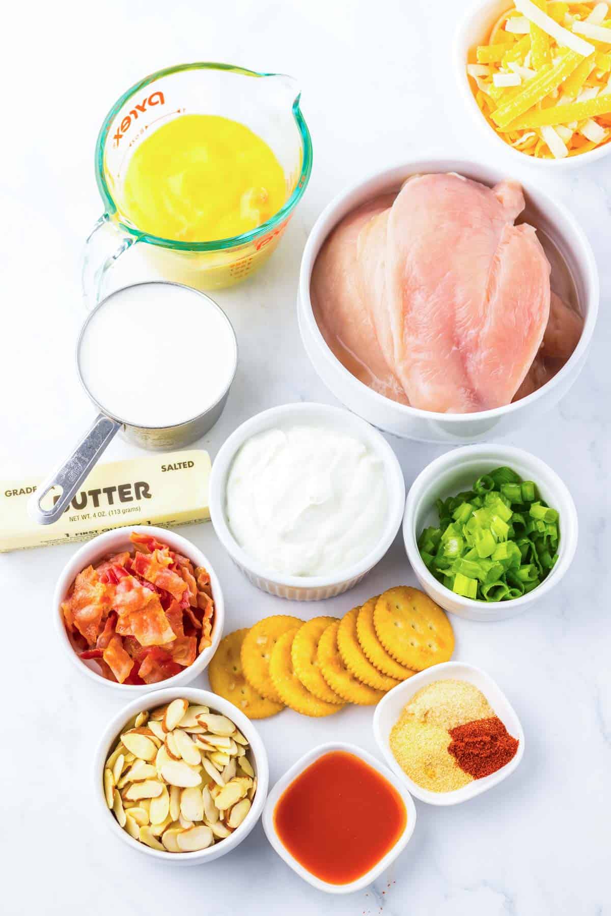 A variety of casserole ingredients, including chicken, butter, crackers, cheese, bacon, yogurt, milk, and seasonings&mdash;perfect for a comforting Neiman Marcus Chicken recipe.