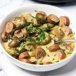 A bowl of creamy soup featuring Swamp Potatoes, tender green beans, chopped herbs, and sliced smoked sausage—perfectly simmered in a slow cooker for rich, comforting flavor.