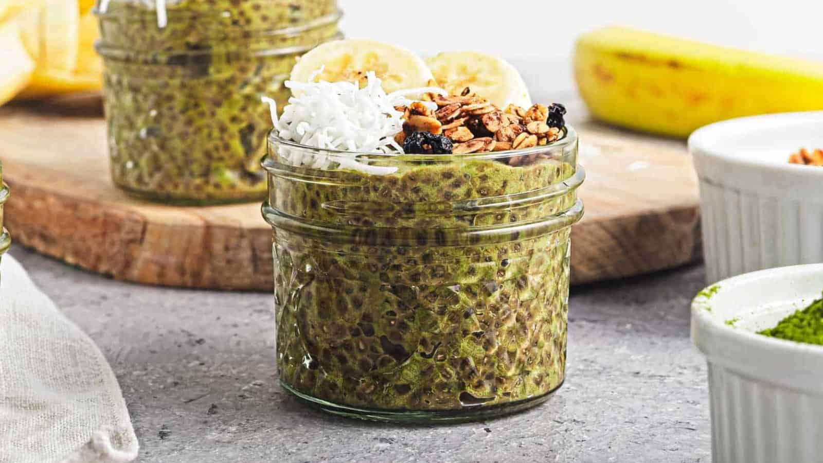 A jar of banana matcha chia pudding on a gray counter.