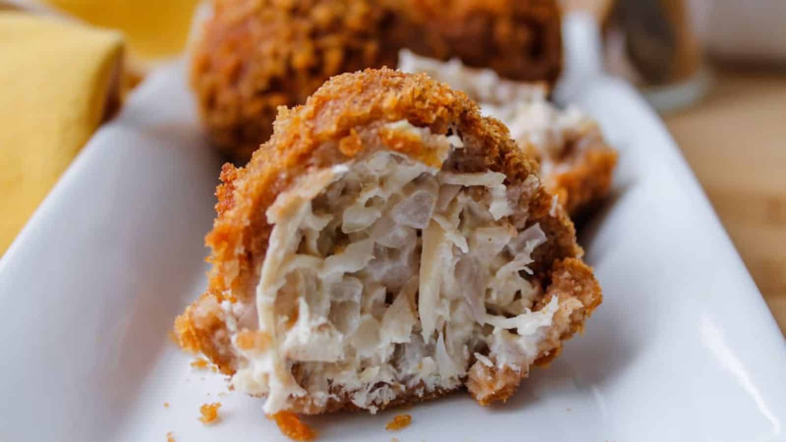 A Brazilian Coxinha on a serving plate with a bite taken out of it.