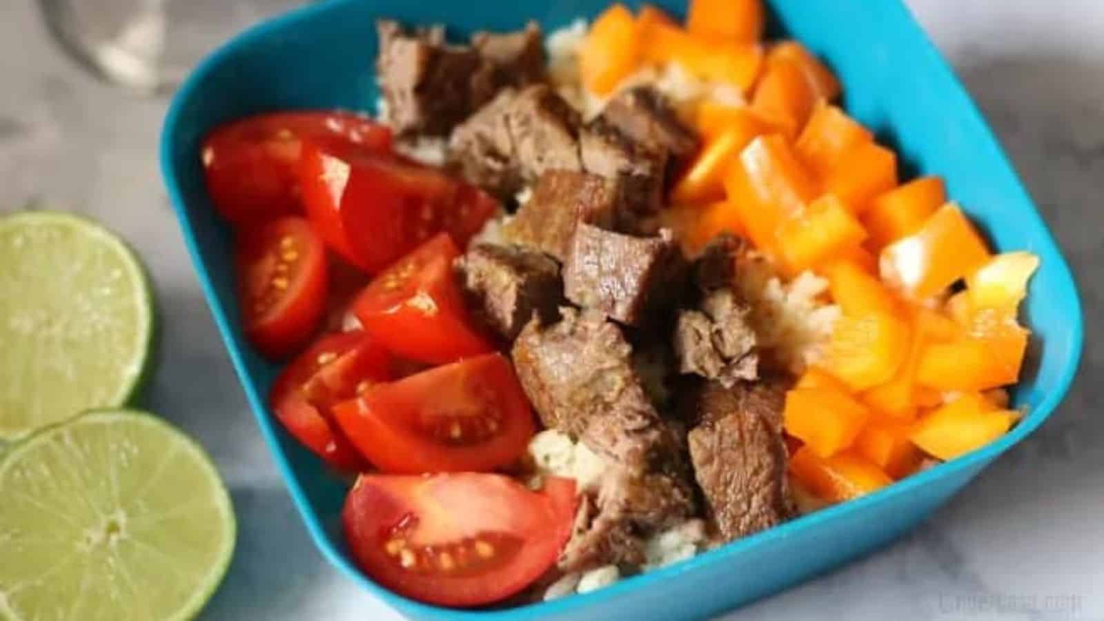 Steak burrito bowl next to sliced limes.