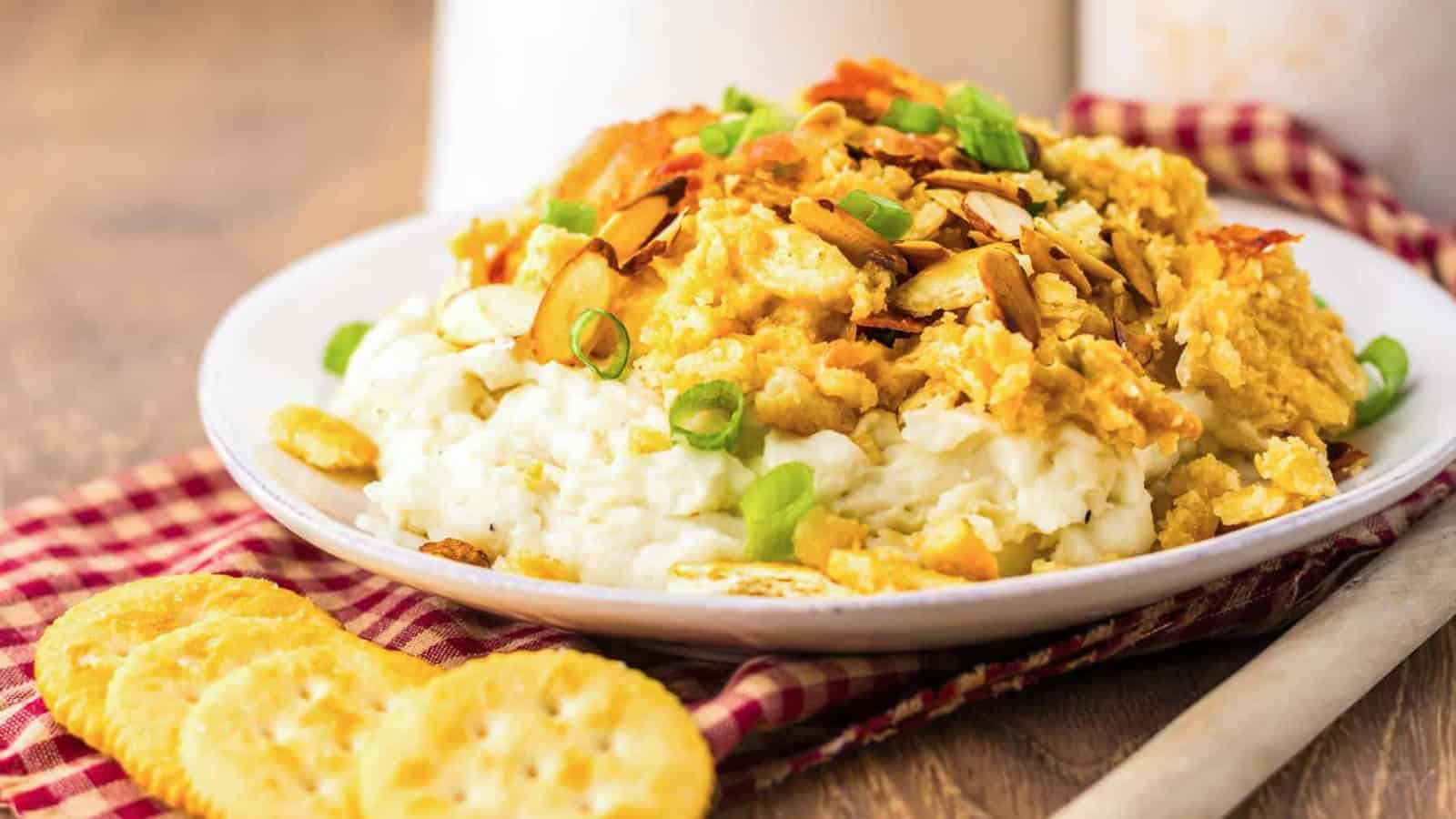 Plate of creamy chicken casserole topped with sliced almonds and green onions, served with crackers.