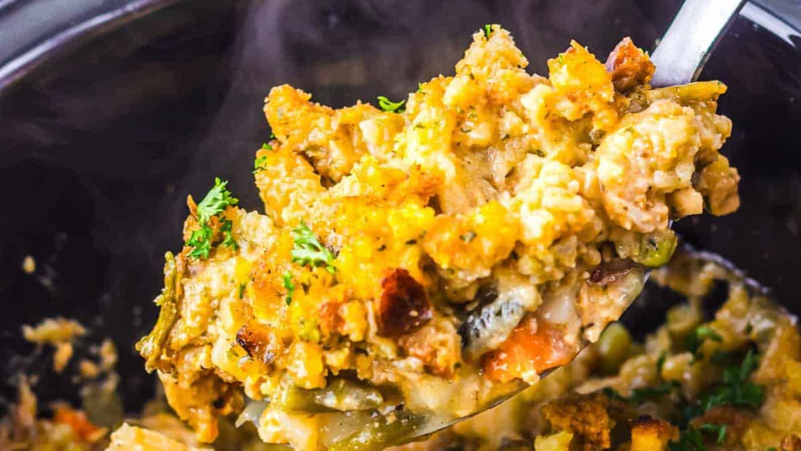 A spoonful of creamy chicken and stuffing casserole garnished with herbs.