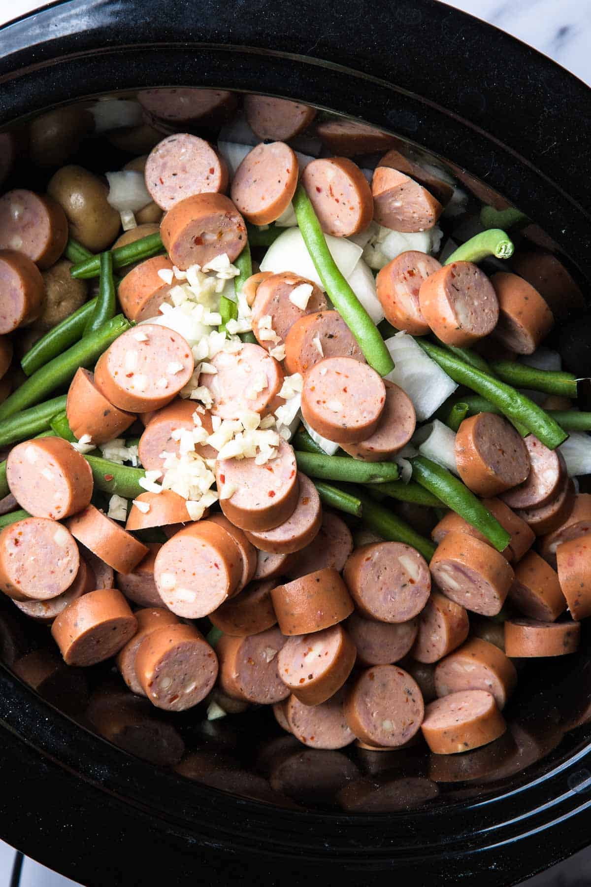 Sliced smoked sausage, green beans, potatoes, onions, and minced garlic come together in this Slow Cooker Swamp Potatoes recipe.