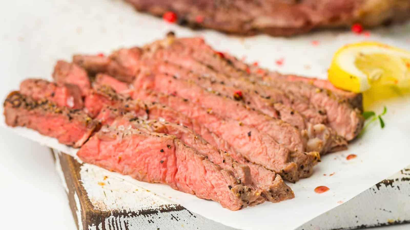 Close-up of a stack of medium-rare, seasoned steak slices, showcasing a pink and juicy interior with a seared crust.