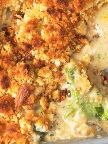 Casserole dish with golden, crispy topping and creamy filling of vegetables, with a spoon scooping some out.
